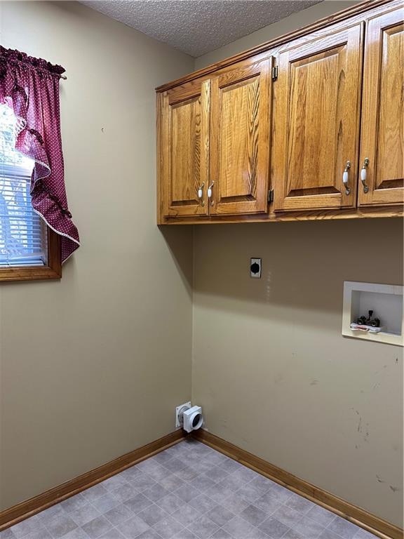 laundry room featuring cabinets, washer hookup, a textured ceiling, and electric dryer hookup