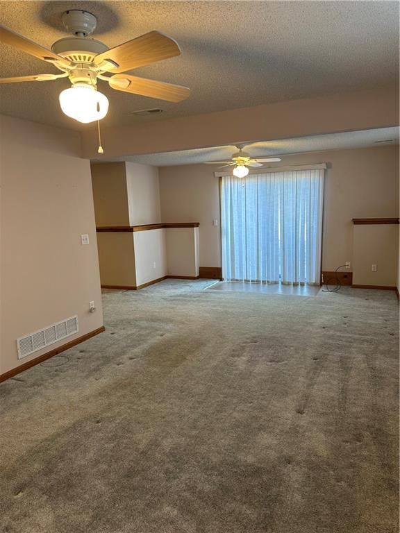 carpeted spare room featuring ceiling fan and a textured ceiling