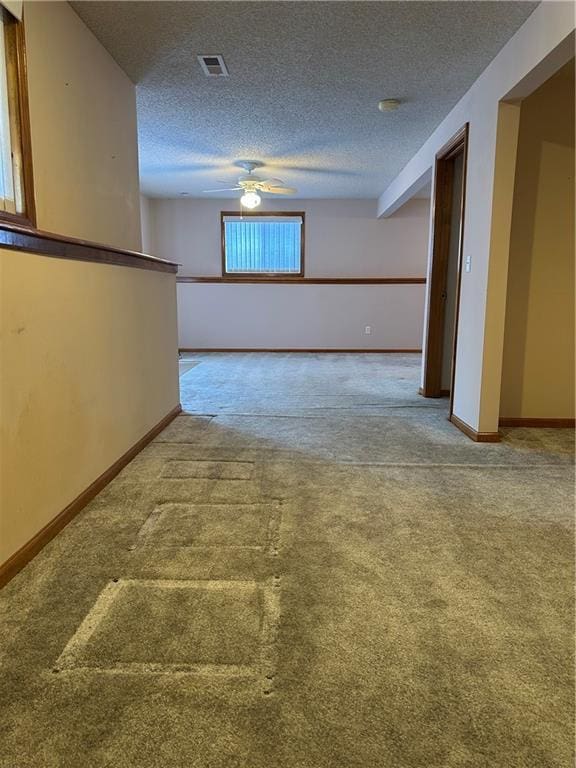 empty room with ceiling fan, carpet floors, and a textured ceiling