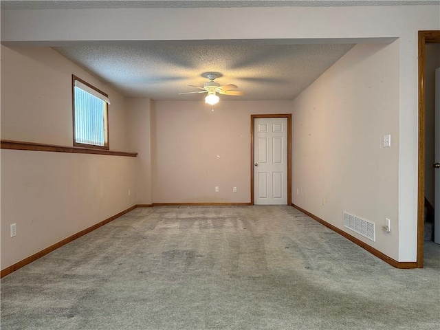 spare room with ceiling fan, light colored carpet, and a textured ceiling