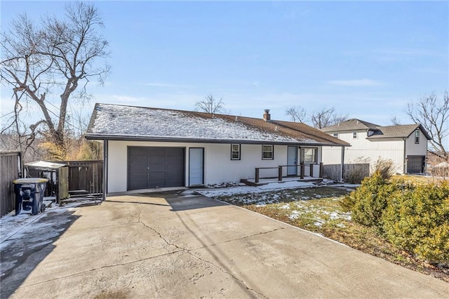 ranch-style home with concrete driveway, a chimney, an attached garage, and fence