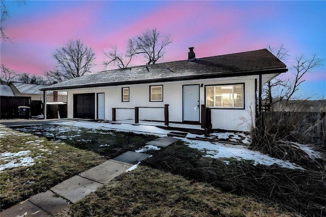 view of front facade with a chimney, roof with shingles, an attached garage, and fence