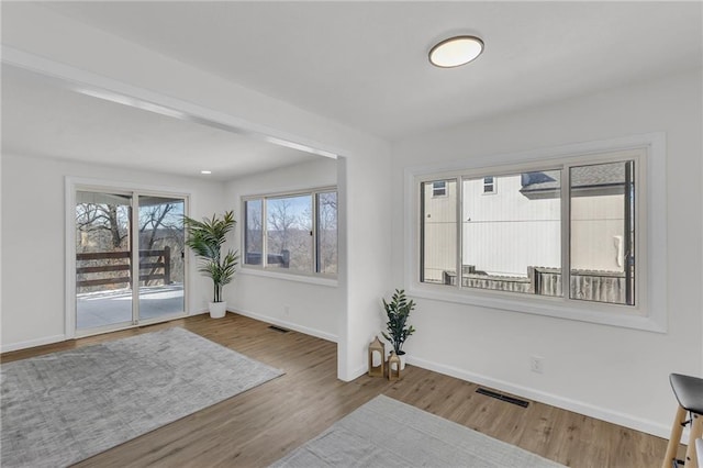 interior space with wood finished floors, visible vents, and baseboards