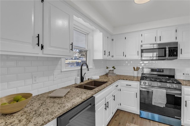 kitchen with stainless steel appliances, white cabinetry, and a sink