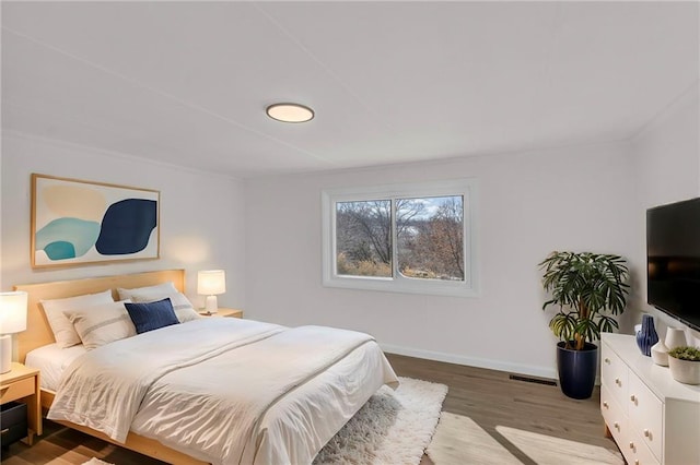 bedroom with wood finished floors, visible vents, and baseboards