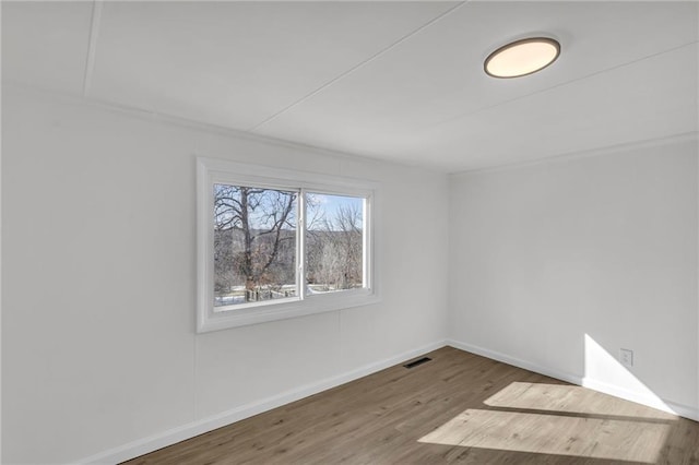 unfurnished room featuring visible vents, baseboards, and wood finished floors