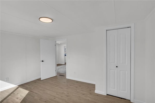 unfurnished bedroom featuring a closet, wood finished floors, and baseboards