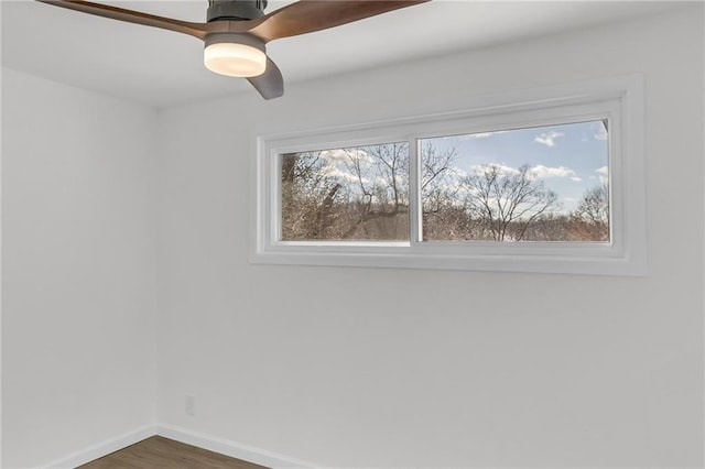 unfurnished room with a ceiling fan, wood finished floors, a wealth of natural light, and baseboards