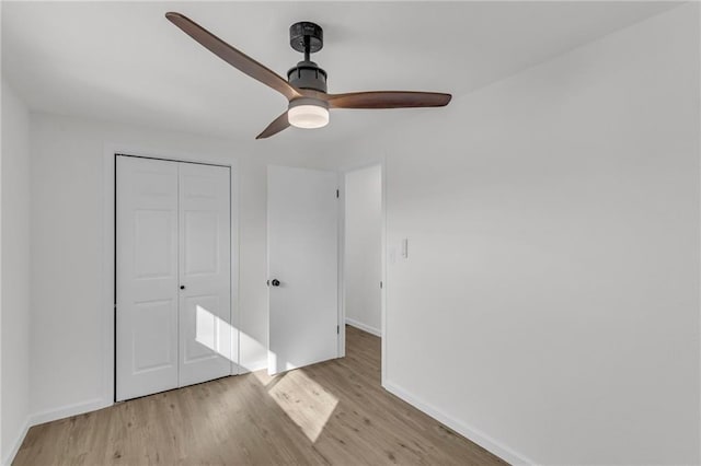 unfurnished bedroom featuring ceiling fan, a closet, baseboards, and wood finished floors