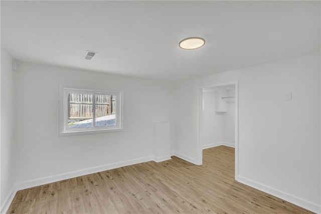 unfurnished room with light wood-style flooring, visible vents, and baseboards