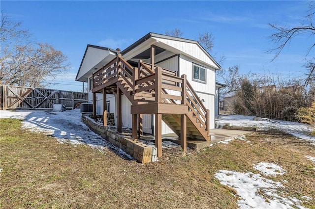 snow covered back of property with stairway, cooling unit, a wooden deck, and fence