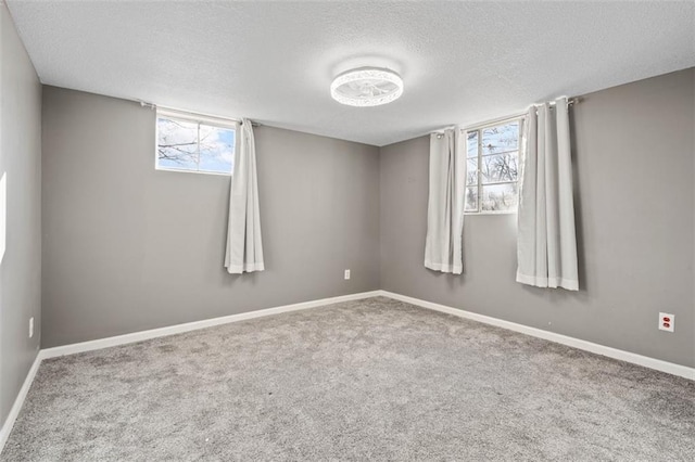 carpeted empty room with a healthy amount of sunlight, baseboards, and a textured ceiling