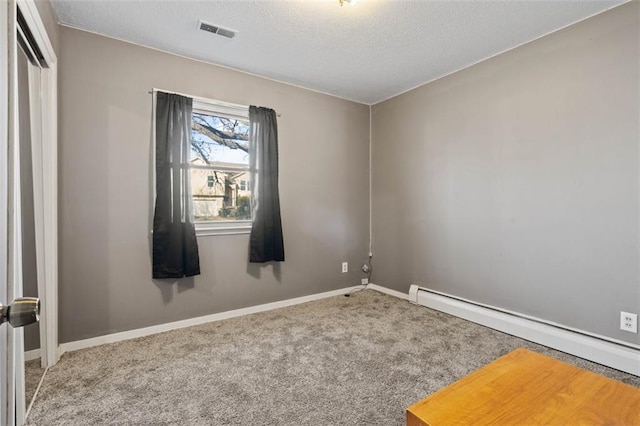 carpeted empty room featuring baseboards, visible vents, a textured ceiling, and baseboard heating