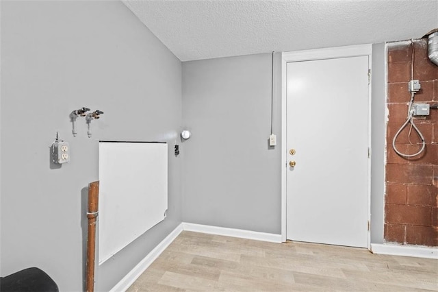 interior space with a textured ceiling, wood finished floors, and baseboards