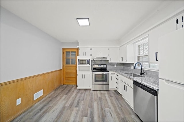 kitchen featuring light hardwood / wood-style flooring, appliances with stainless steel finishes, sink, white cabinetry, and light stone countertops