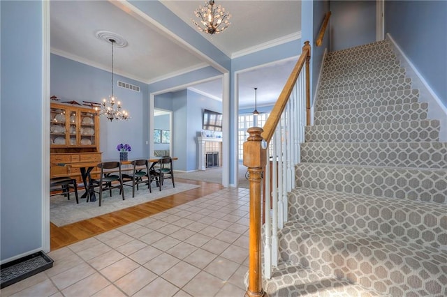 stairway featuring crown molding, tile patterned floors, visible vents, and a notable chandelier