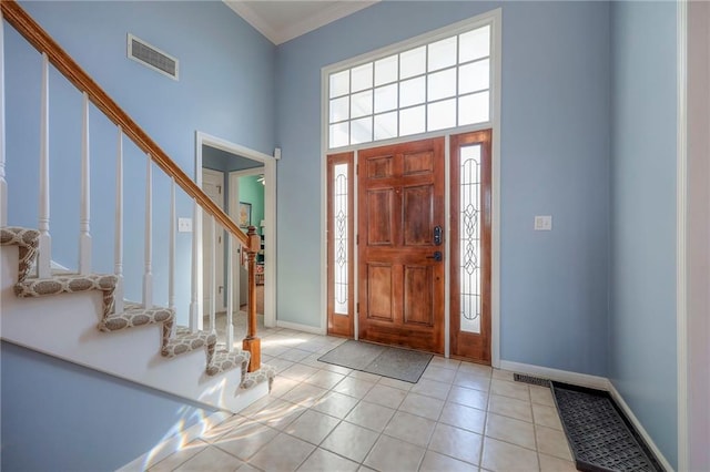 entryway with visible vents, a towering ceiling, light tile patterned flooring, baseboards, and stairs