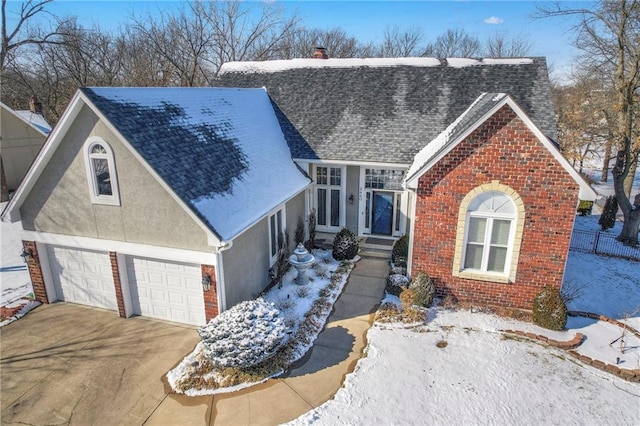 view of front facade with a garage, brick siding, a shingled roof, concrete driveway, and stucco siding