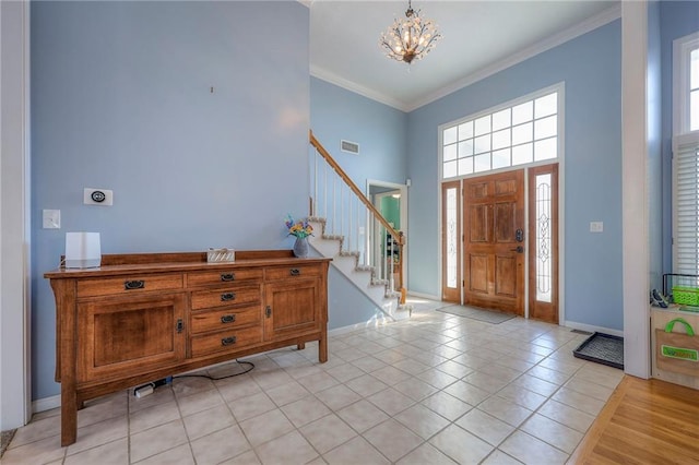 entrance foyer featuring a notable chandelier, crown molding, light tile patterned flooring, baseboards, and stairs