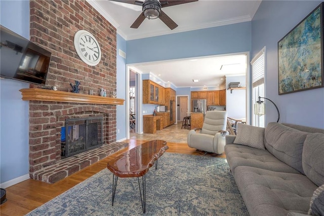 living area with baseboards, light wood-style floors, a brick fireplace, and crown molding