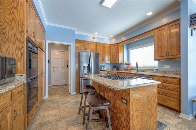 kitchen featuring a kitchen island, a breakfast bar area, brown cabinets, stainless steel appliances, and a sink