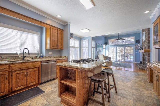 kitchen with brown cabinetry, a kitchen island, appliances with stainless steel finishes, a breakfast bar, and a sink