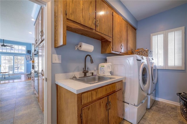 laundry room with cabinet space, baseboards, a sink, and washing machine and clothes dryer