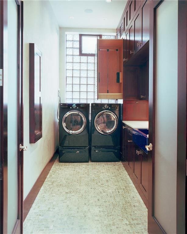 clothes washing area featuring cabinets and washer and clothes dryer