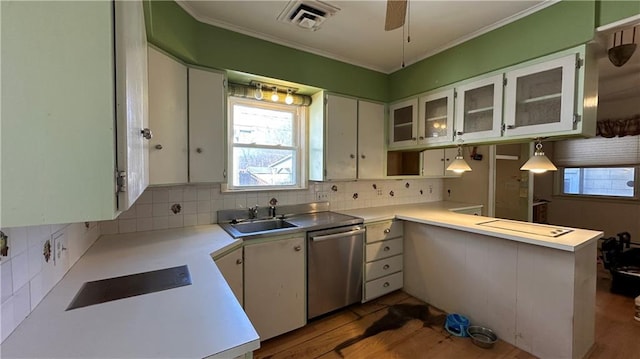 kitchen featuring backsplash, light countertops, ornamental molding, stainless steel dishwasher, and a sink