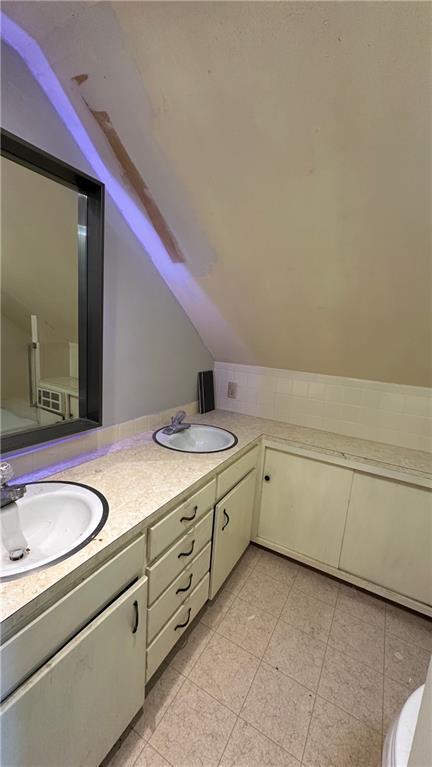 bathroom with double vanity, vaulted ceiling, and a sink