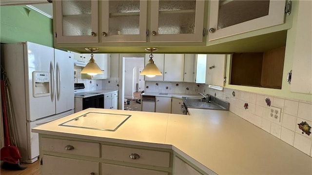 kitchen with decorative backsplash, white appliances, a peninsula, and light countertops