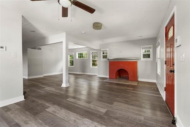 unfurnished living room featuring a fireplace, dark wood-type flooring, and ceiling fan