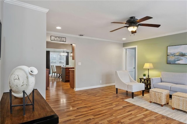 living room with ceiling fan with notable chandelier, ornamental molding, and hardwood / wood-style floors