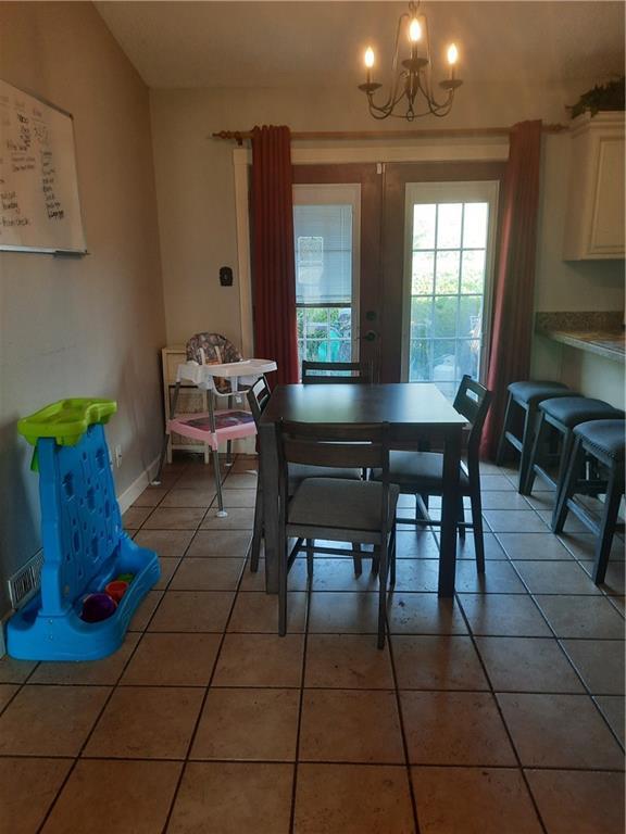 dining space with french doors, tile patterned floors, and a chandelier