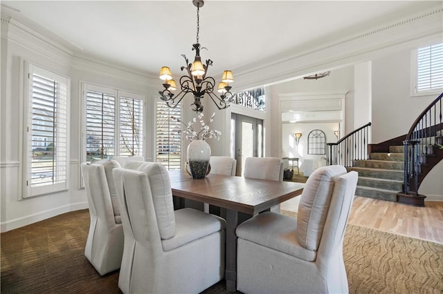 dining room with baseboards, crown molding, an inviting chandelier, and stairs