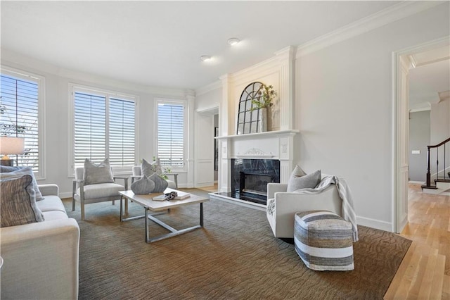 living area featuring light wood-style flooring, a premium fireplace, baseboards, stairs, and ornamental molding