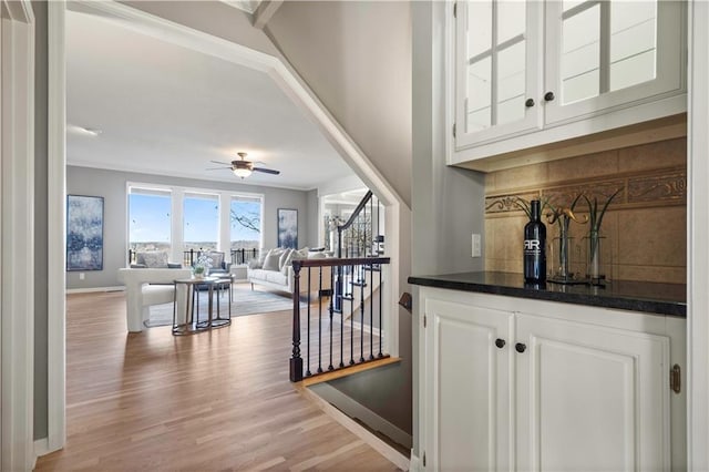 bar with tasteful backsplash, baseboards, a ceiling fan, stairway, and light wood-style floors