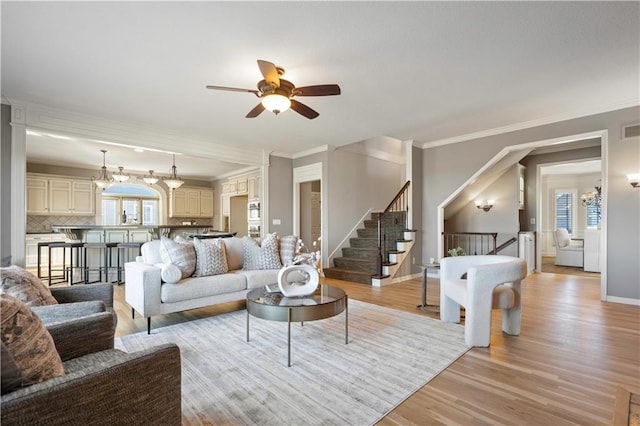 living room featuring stairway, light wood-type flooring, visible vents, and baseboards