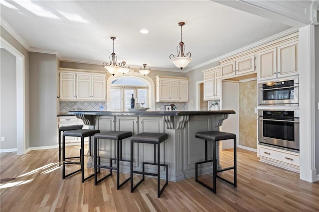 kitchen featuring dark countertops, light wood-style floors, a breakfast bar, and cream cabinetry