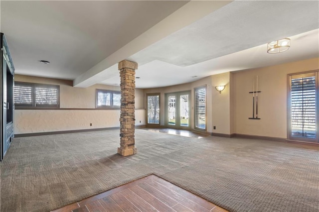 unfurnished living room with french doors, carpet, decorative columns, and baseboards