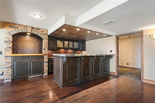 bar with dark wood-type flooring, visible vents, and baseboards