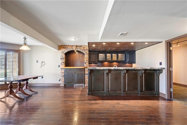 bar with beam ceiling, dark wood-style flooring, visible vents, and baseboards