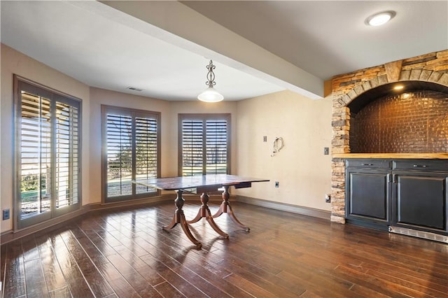 dining room with dark wood-style flooring, visible vents, beamed ceiling, and baseboards