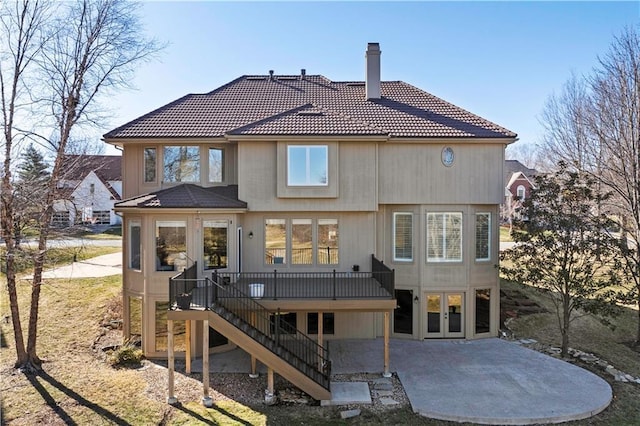 back of property with a patio area, a tile roof, stairs, and a chimney