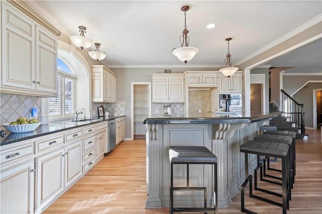 kitchen with a breakfast bar, crown molding, stainless steel appliances, dark countertops, and light wood-style flooring