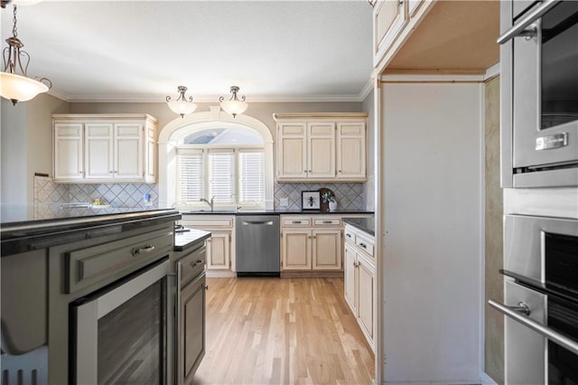 kitchen featuring dark countertops, ornamental molding, cream cabinetry, and dishwasher