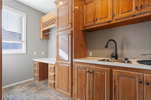 kitchen featuring light countertops, brown cabinetry, and a sink