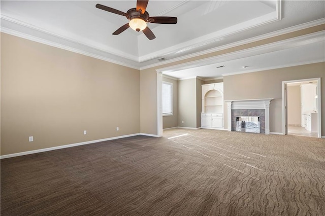 unfurnished living room featuring carpet flooring, baseboards, ornamental molding, a tiled fireplace, and a raised ceiling