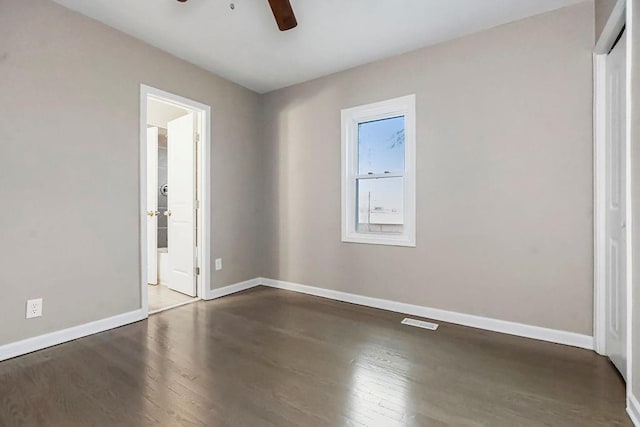 unfurnished bedroom with connected bathroom, dark wood-type flooring, and ceiling fan