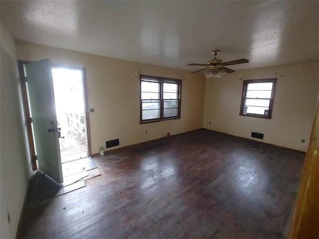 empty room with dark wood-style flooring, ceiling fan, and a textured ceiling